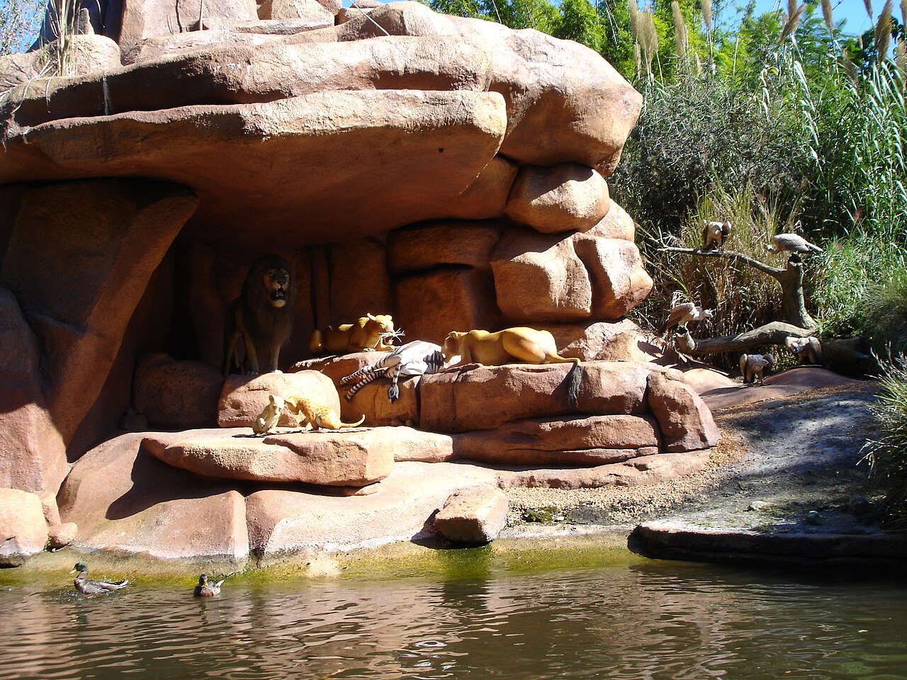 Rochas com leões e girafa animatrônicos no rio do Jungle Cruise