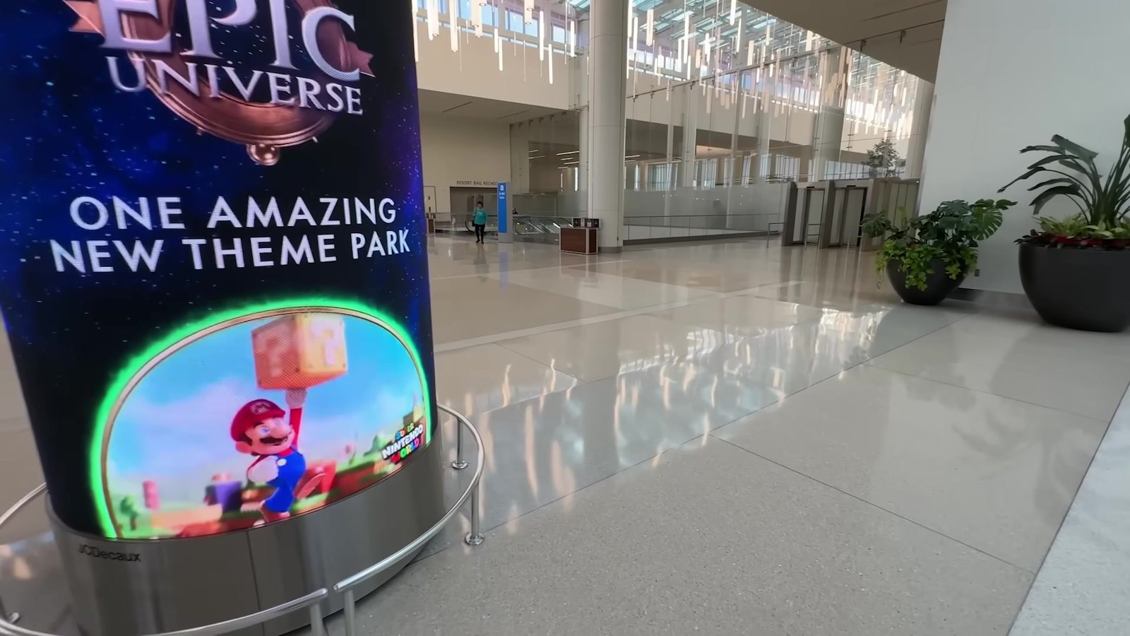 Saguão do Terminal C do aeroporto de Orlando com painel do Epic Universe