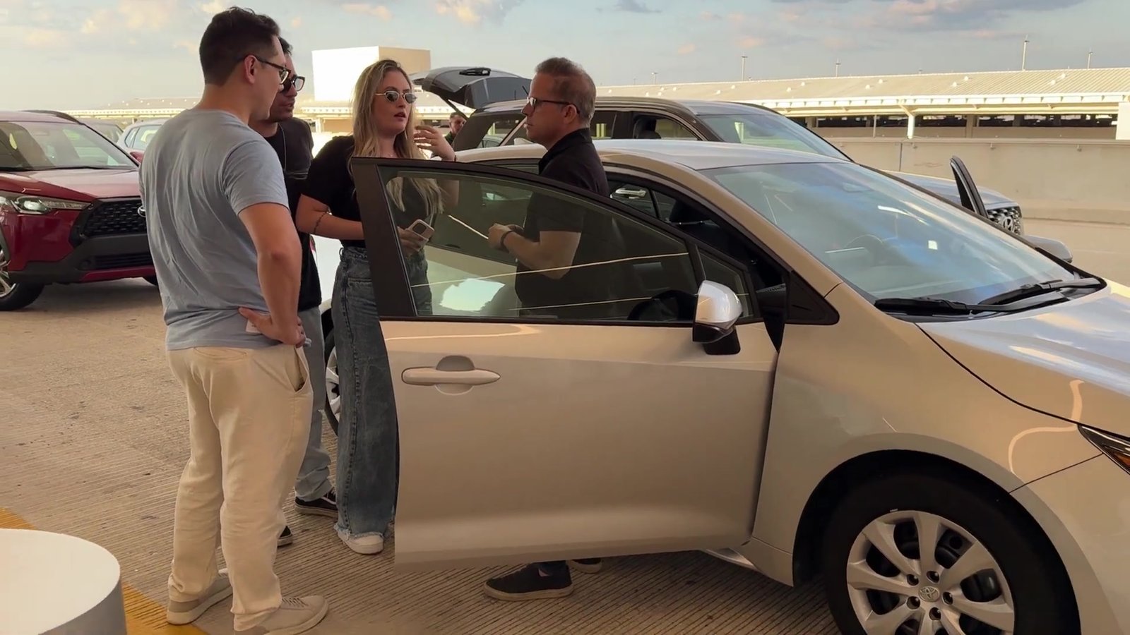 Atendente da locadora entregando um Corolla à família na garagem do aeroporto de Orlando