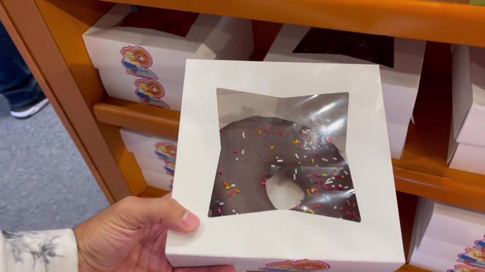 Donut rosa gigante com confeitos dentro da caixa branca do Lard Lad em Springfield