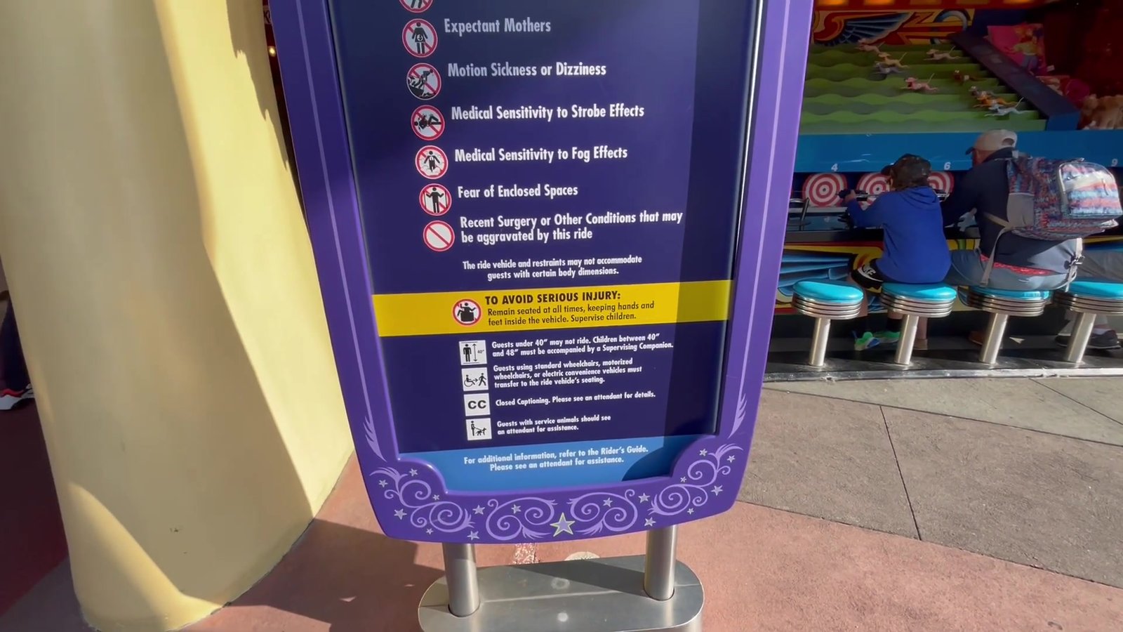 Placa de restrições do Simpsons Ride listando gestantes, enjoo, sensibilidade a luz e claustrofobia