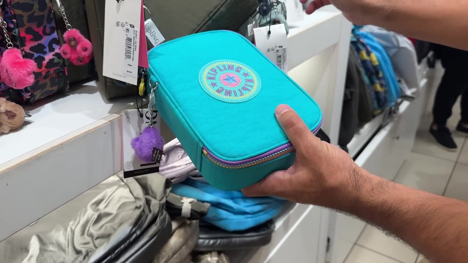 Estojo Kipling verde-água na mão, na loja da Kipling do outlet