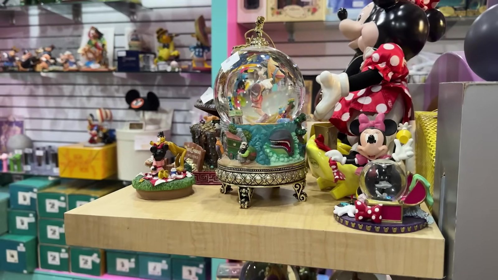 Globo de neve da Pequena Sereia com base dourada, entre estatuetas do Mickey e da Minnie