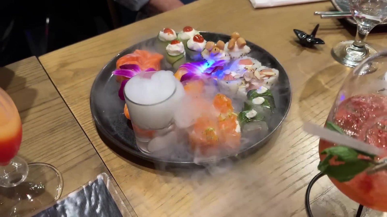 Prato de sushi com gelo seco e drinks coloridos no American Japa, dentro do Magic Village