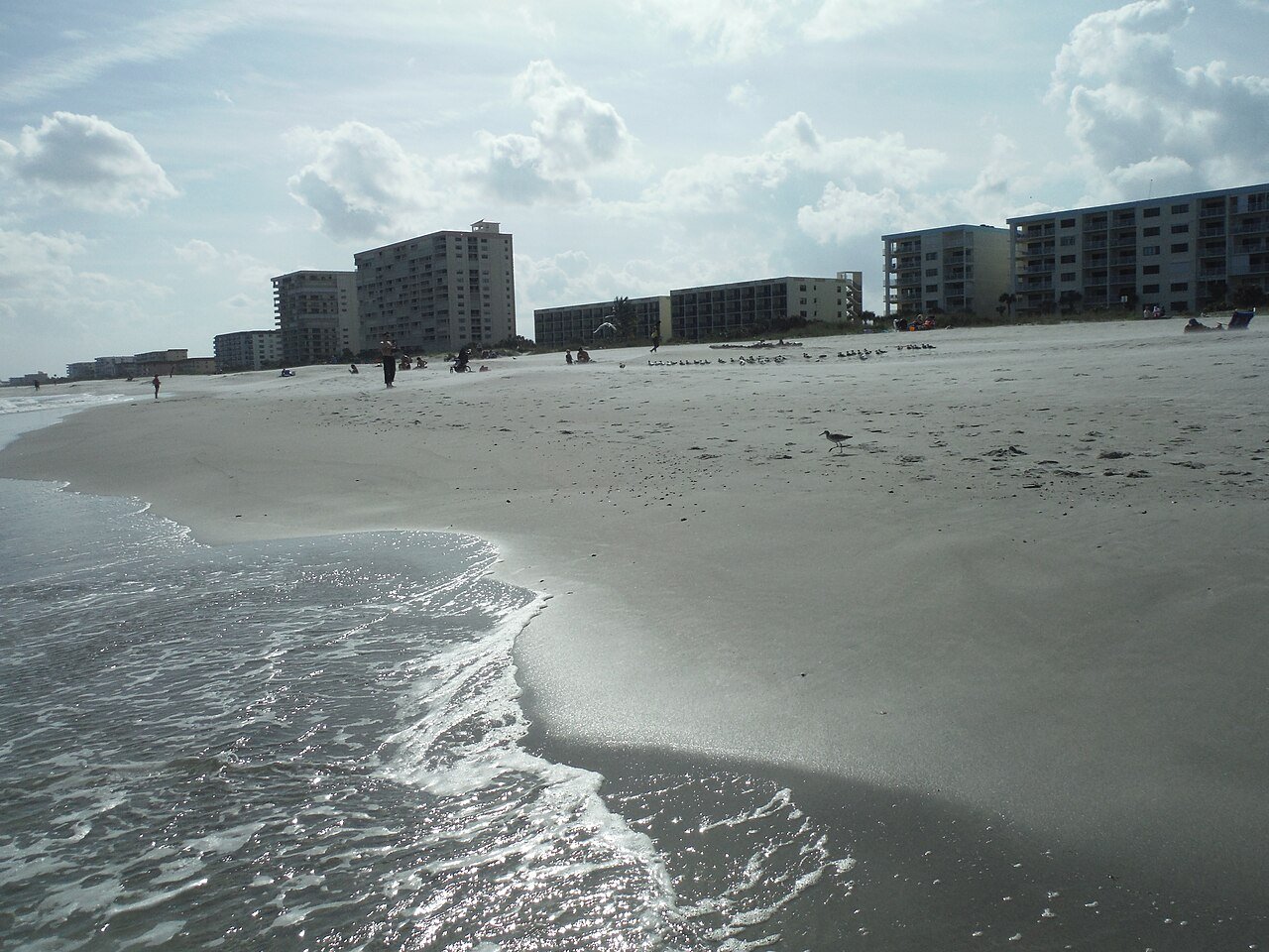 Praia de Cocoa Beach, na Flórida, com ondas e prédios ao fundo