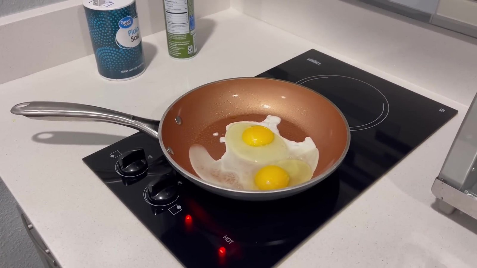 Ovos fritando na frigideira sobre o fogão de indução do quarto de hotel