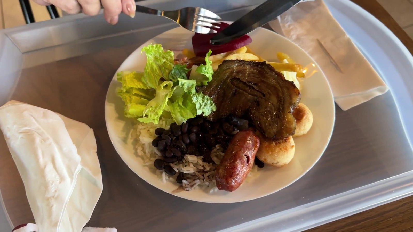 Prato montado no Laçador Grill com picanha, linguiça, feijão preto, farofa e alface