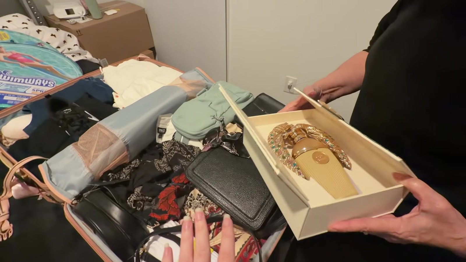 Mão segurando a caixa aberta de um perfume comprado em Orlando