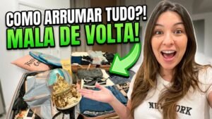 Gabi mostrando a mala aberta cheia de compras de Orlando, com o globo de neve em destaque