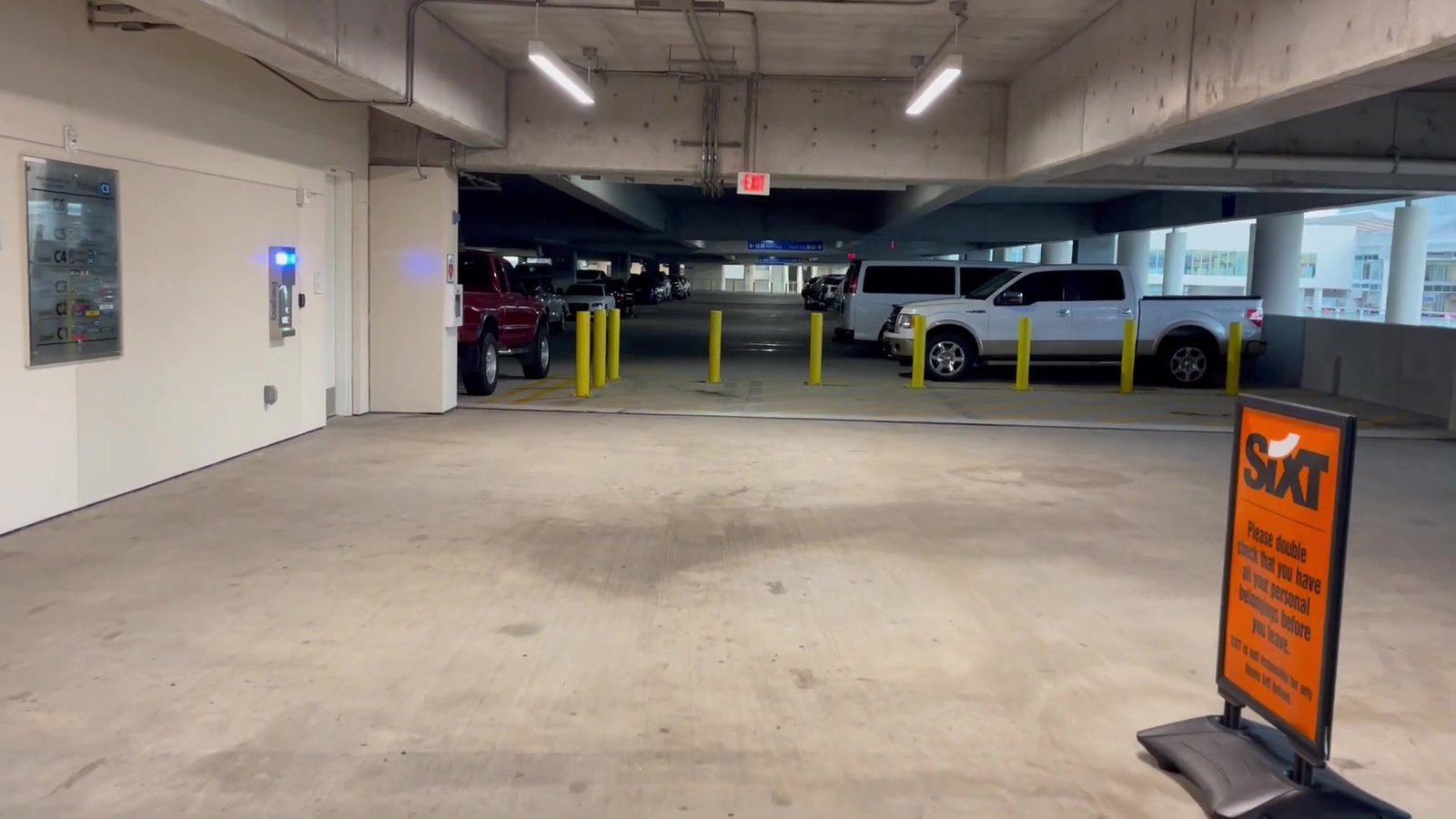 Interior da garagem do Terminal C com a placa da locadora Sixt