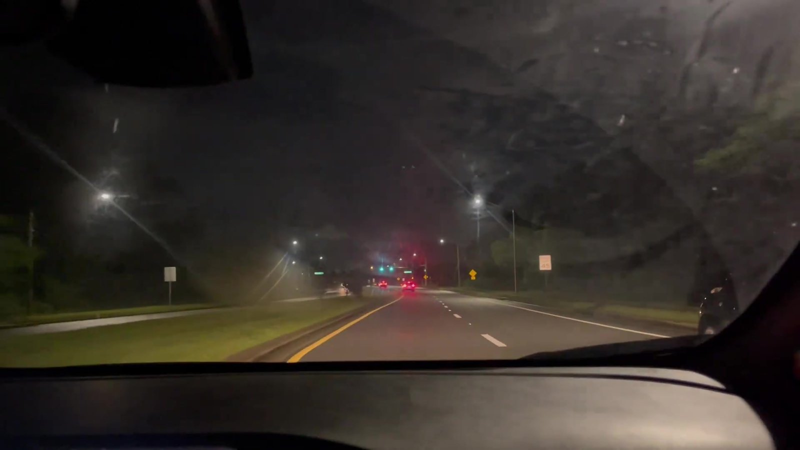 Estrada à noite com semáforo vermelho ao fundo na volta do aeroporto para Celebration