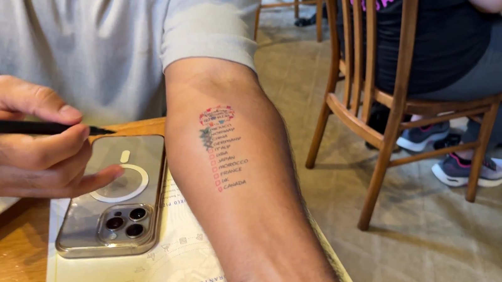 Tatuagem temporária com a lista dos 11 países do World Showcase sendo aplicada no braço