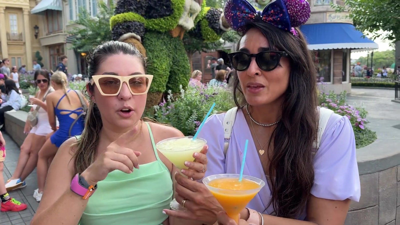 Gabi e amiga segurando os slushies de limão e de laranja no Pavilhão da França do Epcot