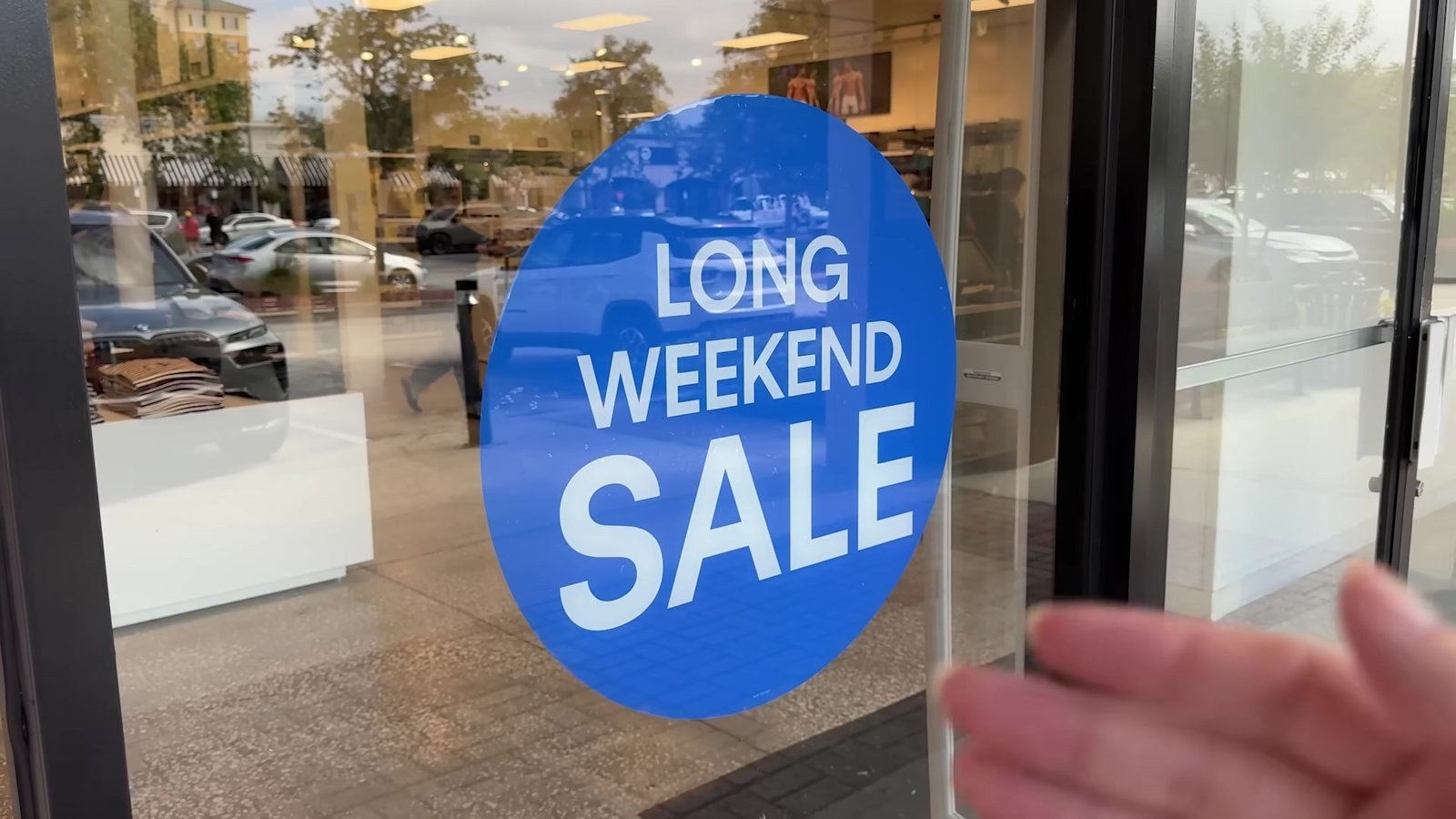 Placa azul de Long Weekend Sale na vitrine de uma loja do outlet de Orlando