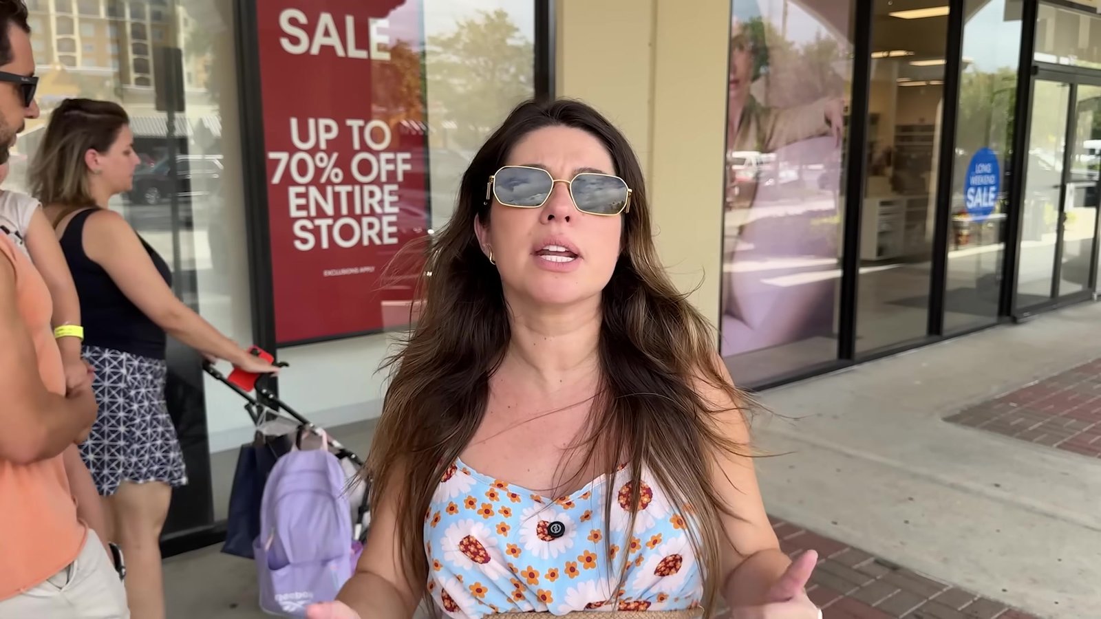 Gabi na porta de uma loja do outlet com a placa Sale Up to 70% Off Entire Store