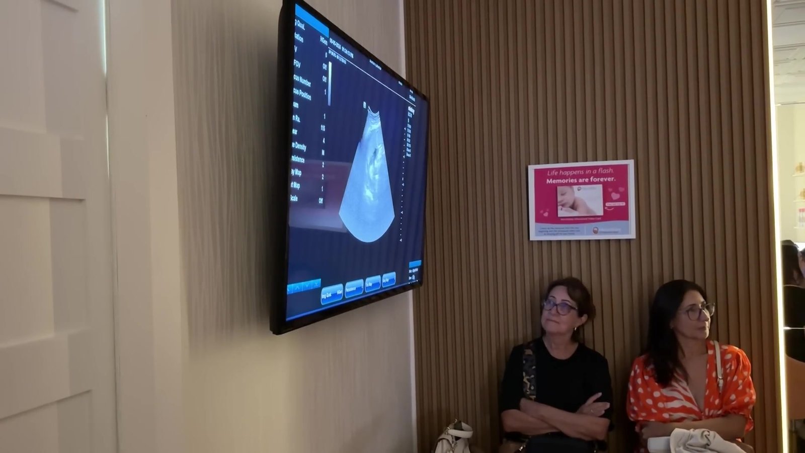 Tela com imagem de ultrassom e duas mulheres sentadas na sala de ultrassom da MacroBaby