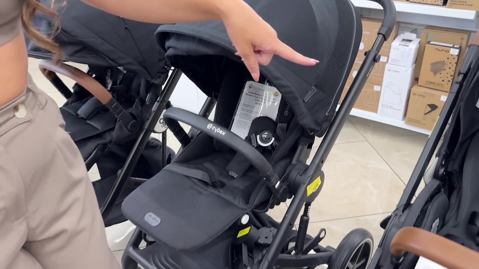Vendedora mostrando o encaixe de um carrinho de bebê preto na MacroBaby