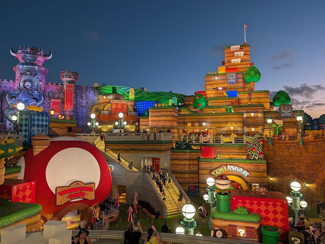 Super Nintendo World no Epic Universe à noite, com o castelo do Bowser e a área do Yoshi