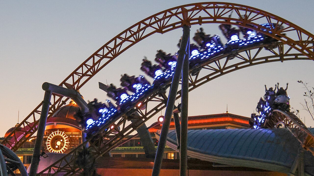 Trem iluminado da Stardust Racers passando pelo trilho ao entardecer no Celestial Park
