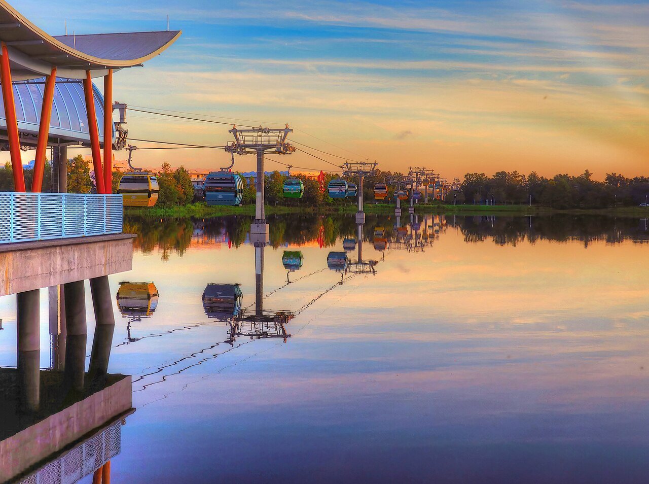 Teleférico Disney Skyliner sobre o lago ao amanhecer, com as gôndolas coloridas