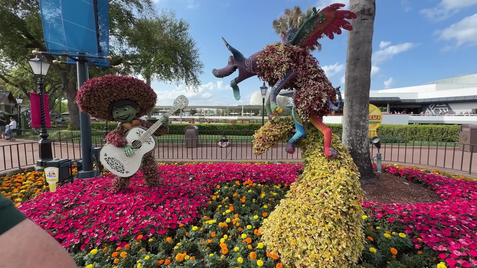 Topiária do Miguel de Coco com violão e o Dante ao lado, cercada de flores, no Epcot