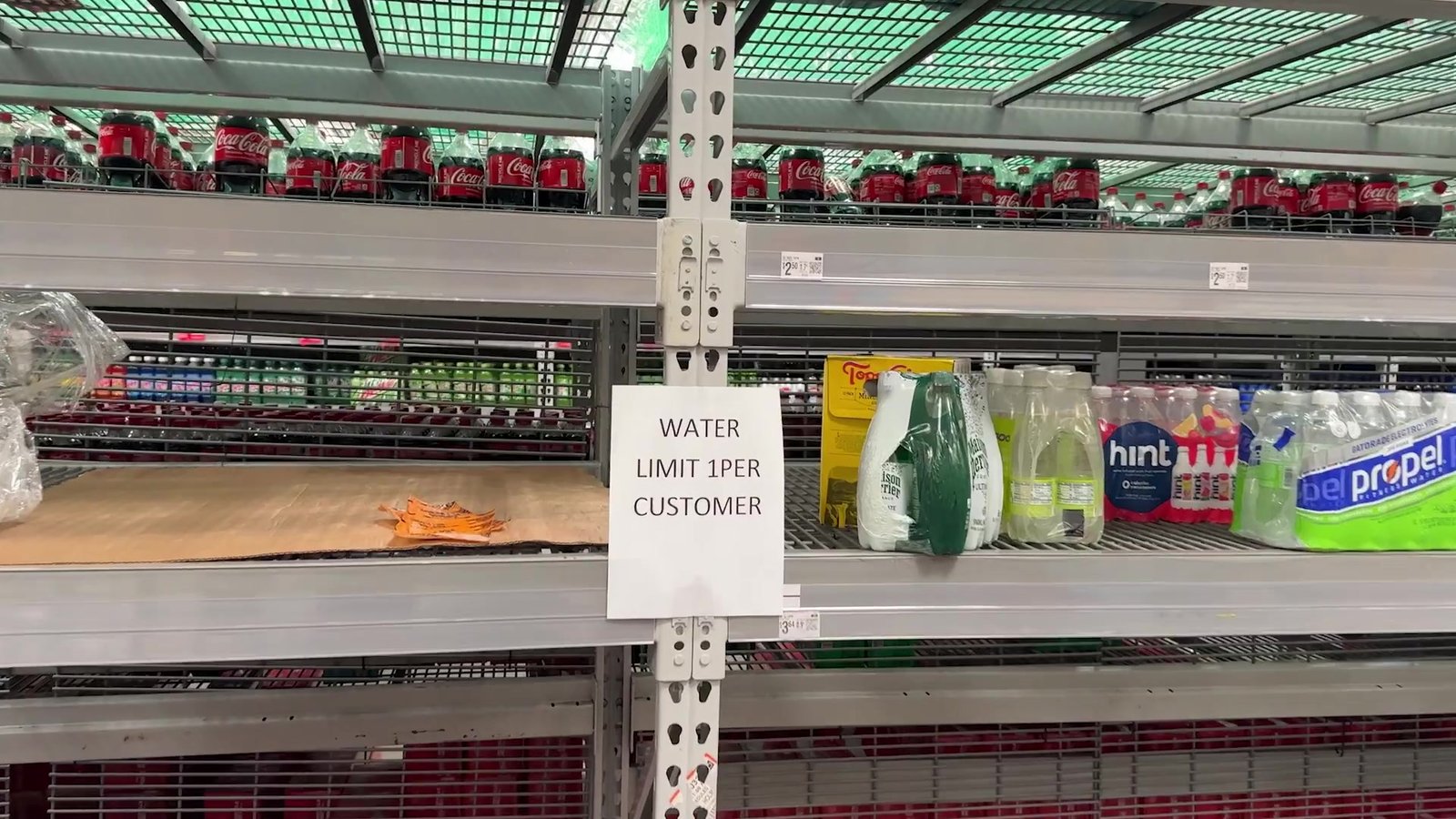 Prateleira de água quase vazia no Walmart com aviso de limite de um fardo por cliente