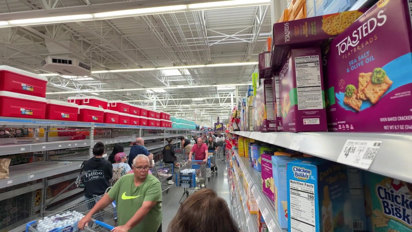 Clientes com carrinhos no corredor de biscoitos e salgadinhos do Walmart antes do furacão