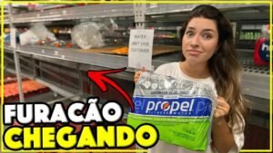Gabi segurando um fardo de água no Walmart, com a prateleira vazia e o aviso de limite por cliente ao fundo