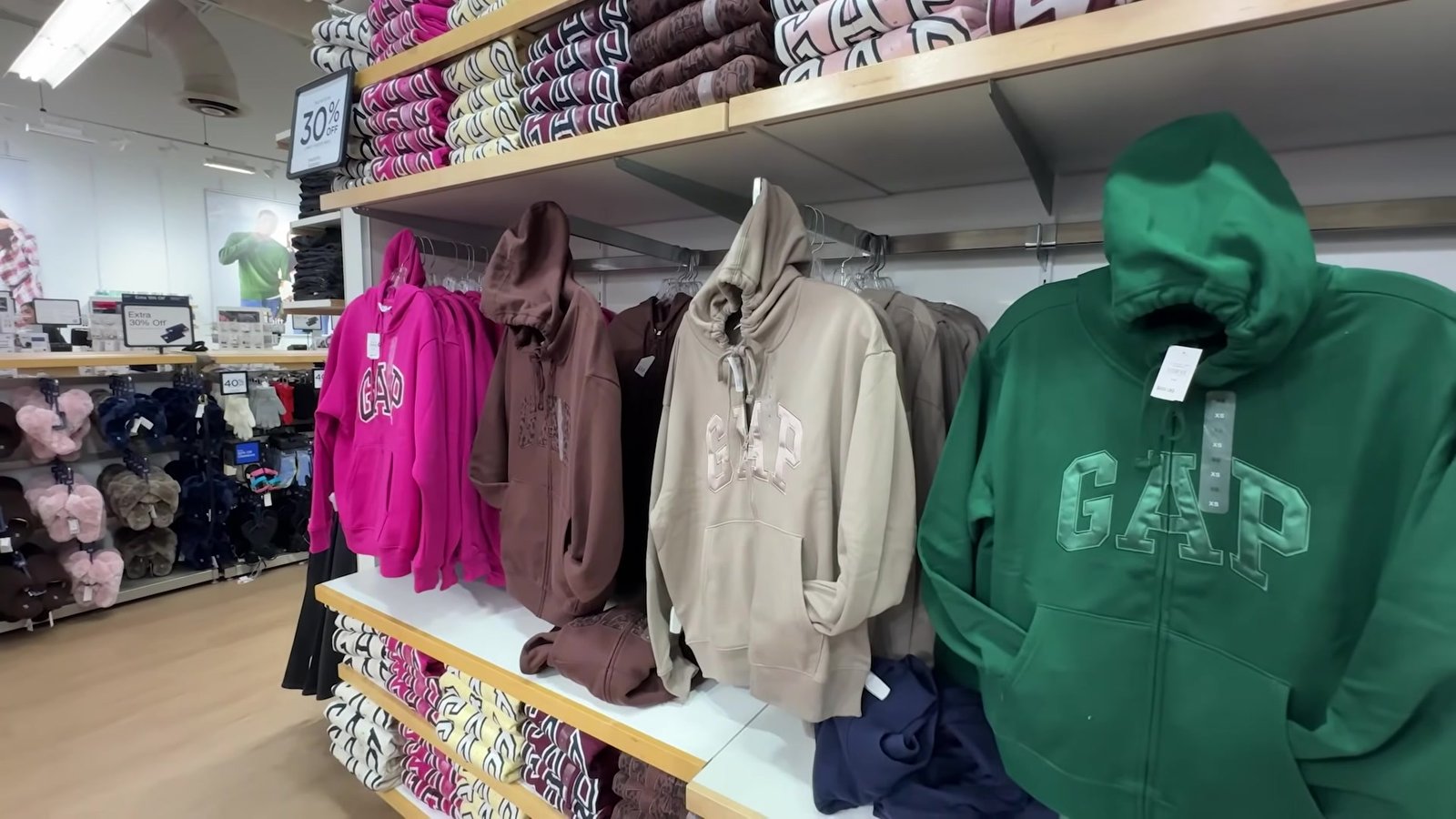 Moletons GAP rosa, marrom e verde com capuz na prateleira com placa de 30% de desconto