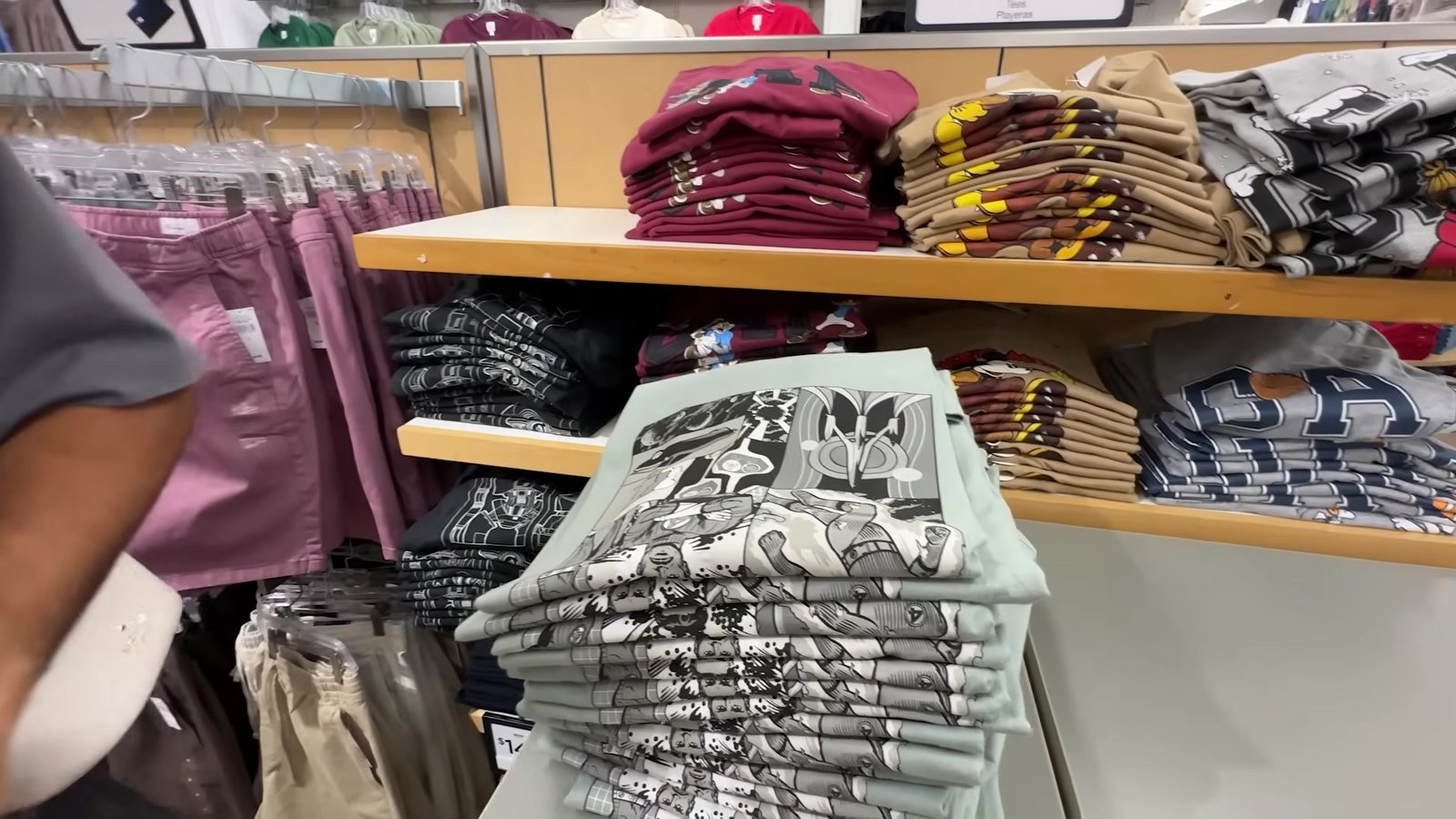 Pilhas de camisetas estampadas e básicas dobradas nas prateleiras da GAP do outlet