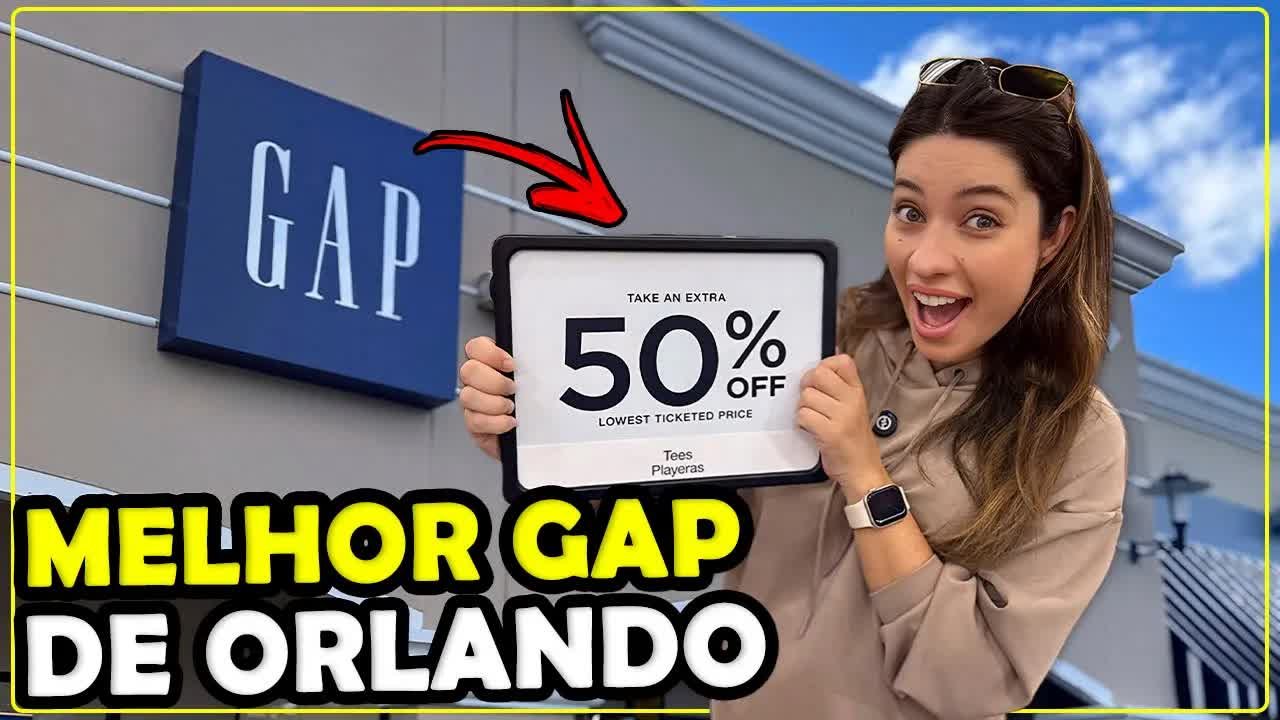 Gabi na frente da GAP do outlet Lake Buena Vista segurando a placa de extra 50% de desconto