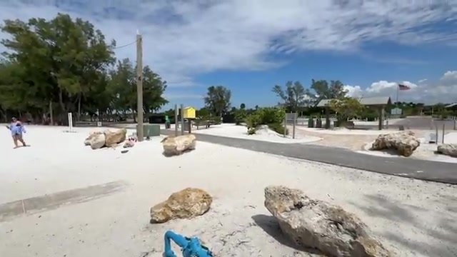 Entrada de Coquina Beach com pedras de coquina na areia e o posto de salva-vidas ao fundo