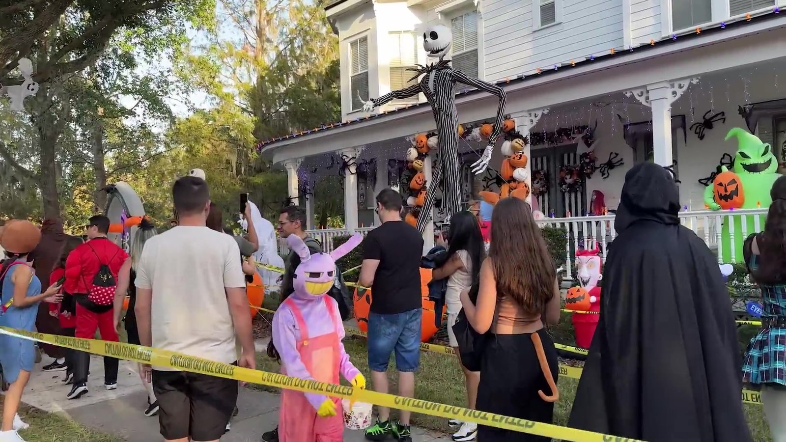 Casa em Celebration com Jack Skellington e Oogie Boogie gigantes na varanda e fila de visitantes fantasiados