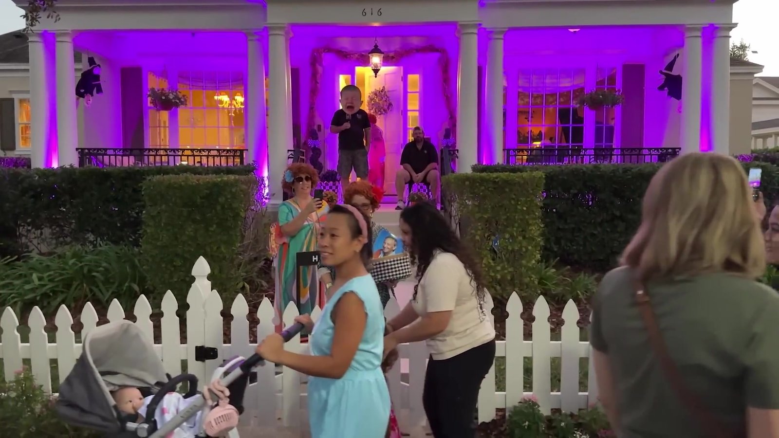 Casa de Celebration iluminada de roxo à noite com famílias fantasiadas na calçada