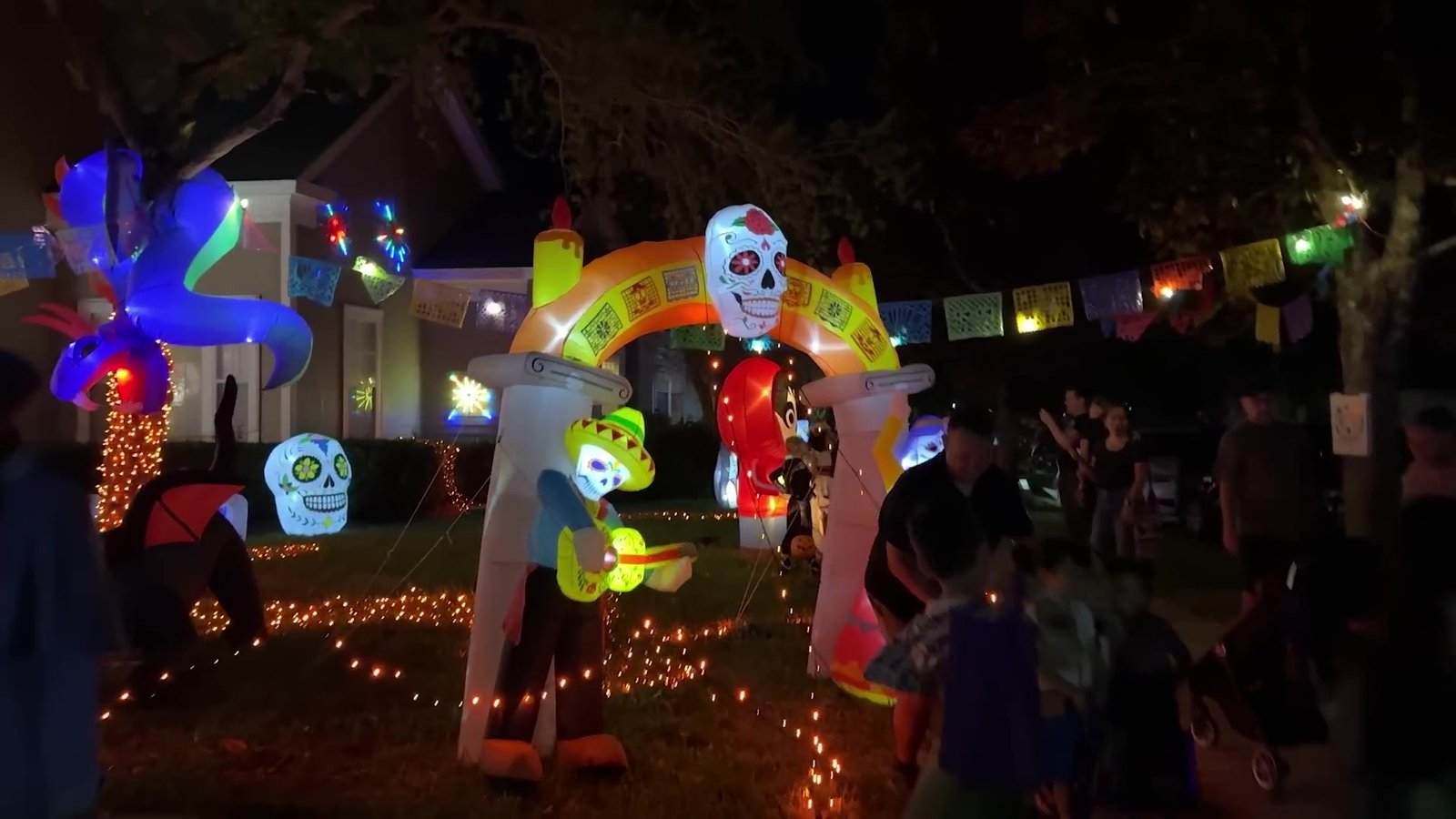Casa decorada com tema do filme Coco em Celebration, com infláveis de caveiras coloridas e bandeirolas à noite