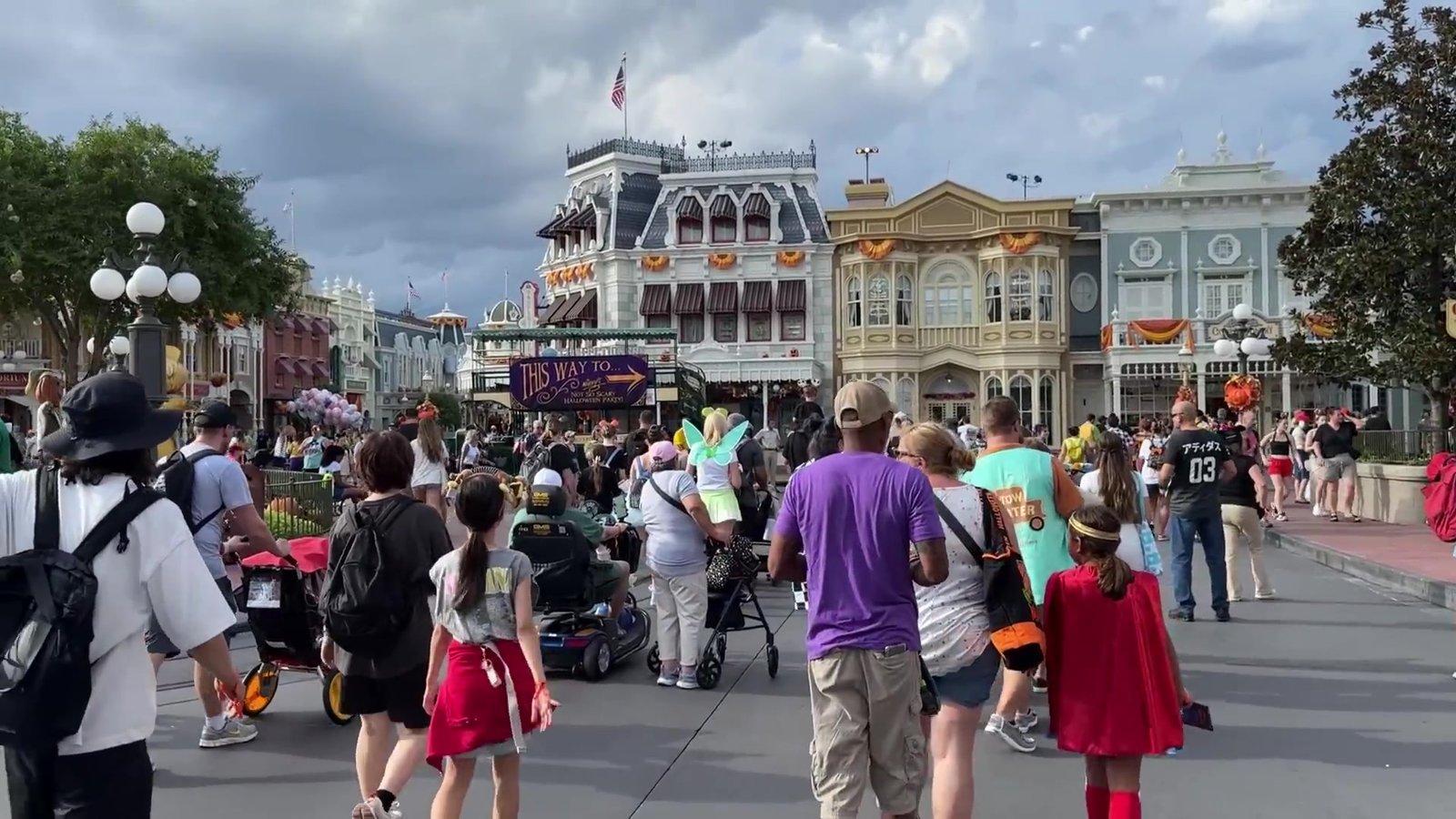 Main Street do Magic Kingdom decorada com abóboras e o público chegando de tarde pra festa de Halloween