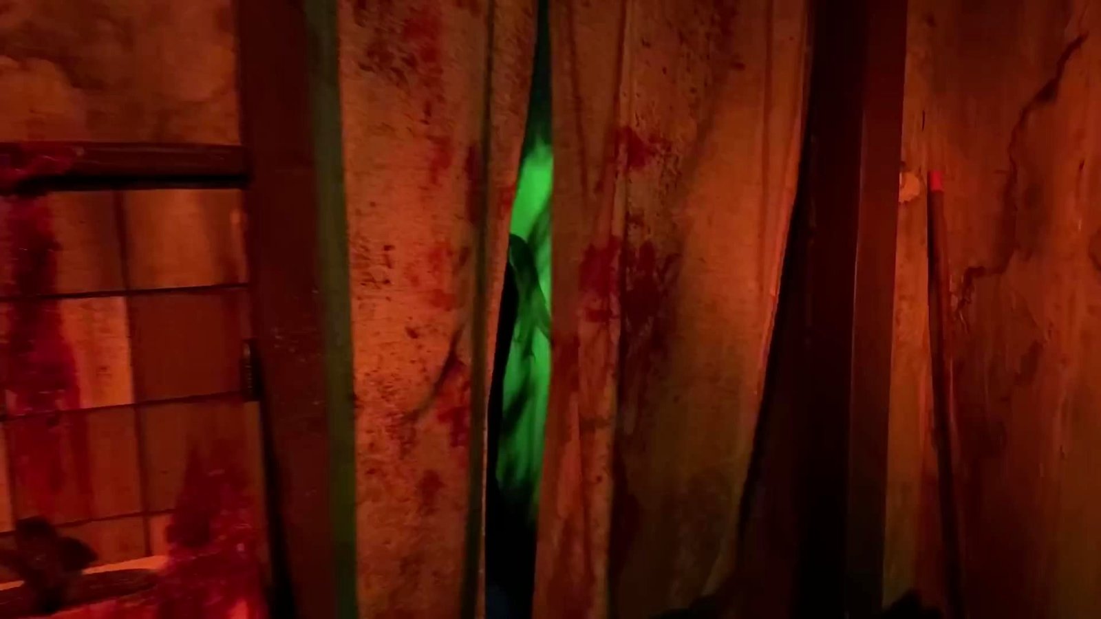Parede manchada de sangue falso e luz verde dentro de uma casa de terror do Halloween Horror Nights