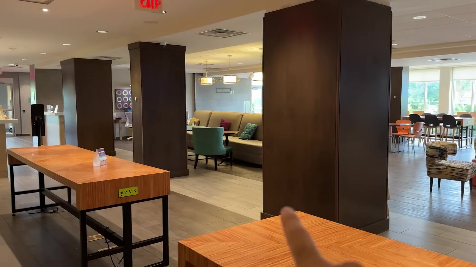 Salão do café da manhã do Home2 Suites com mesas de madeira e poltronas