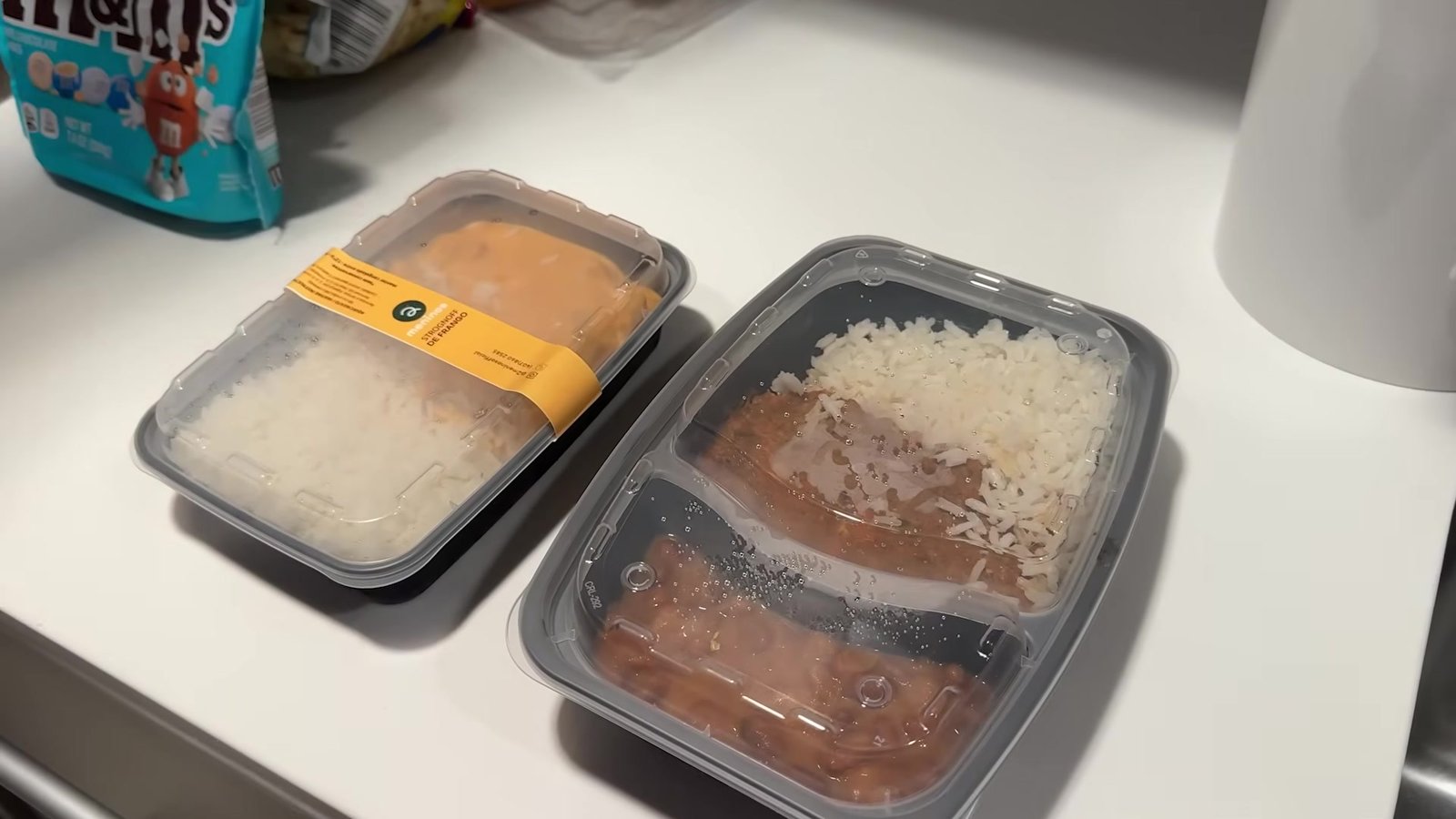Duas marmitas brasileiras de arroz com strogonoff e arroz com feijão na bancada da cozinha do quarto