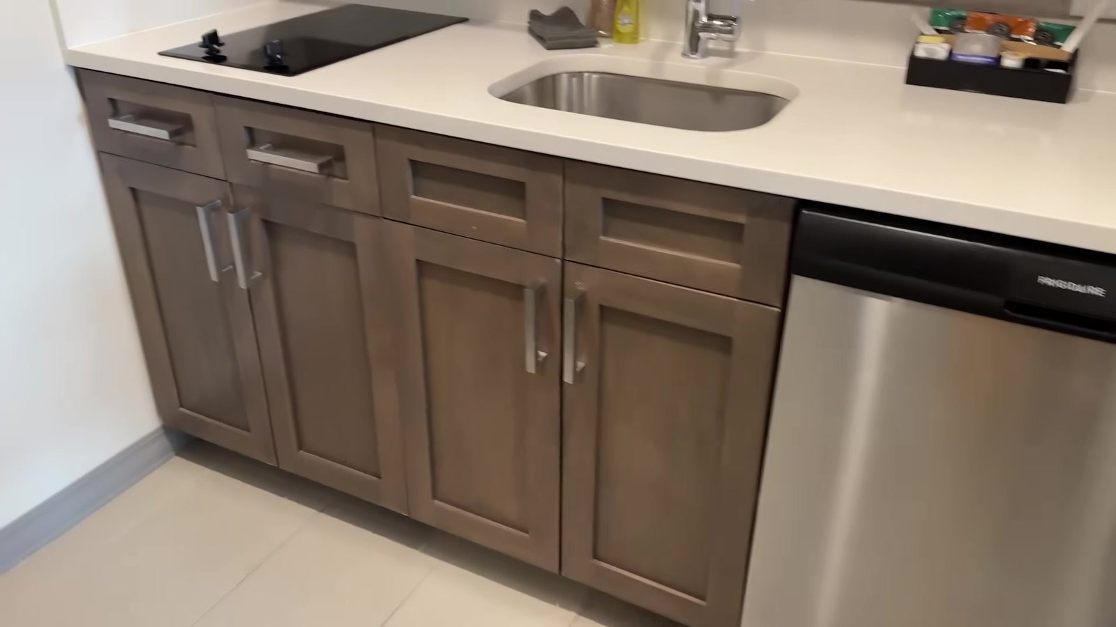 Cozinha do quarto do Homewood Suites com cooktop, pia e lava-louças de inox