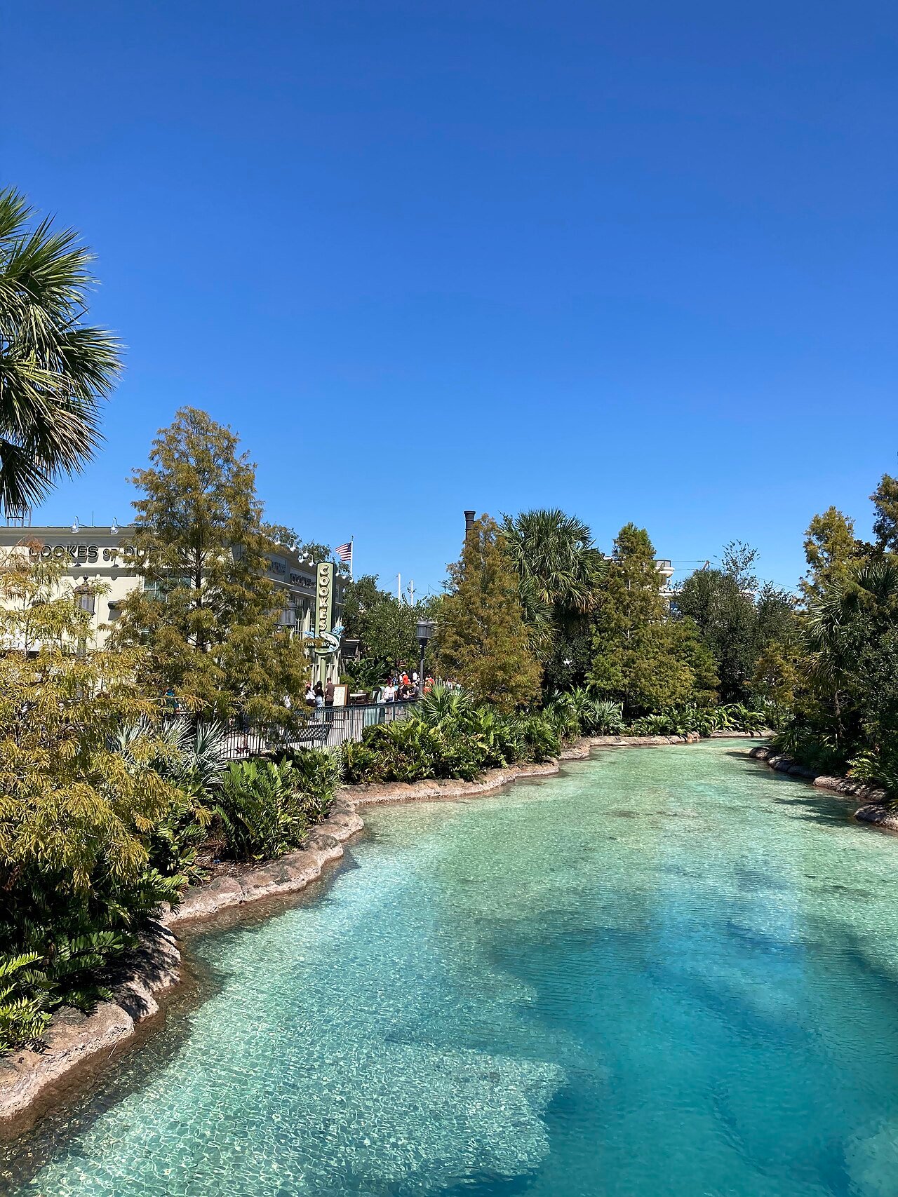 Canal de água cristalina do Disney Springs com a fachada do Cookes of Dublin