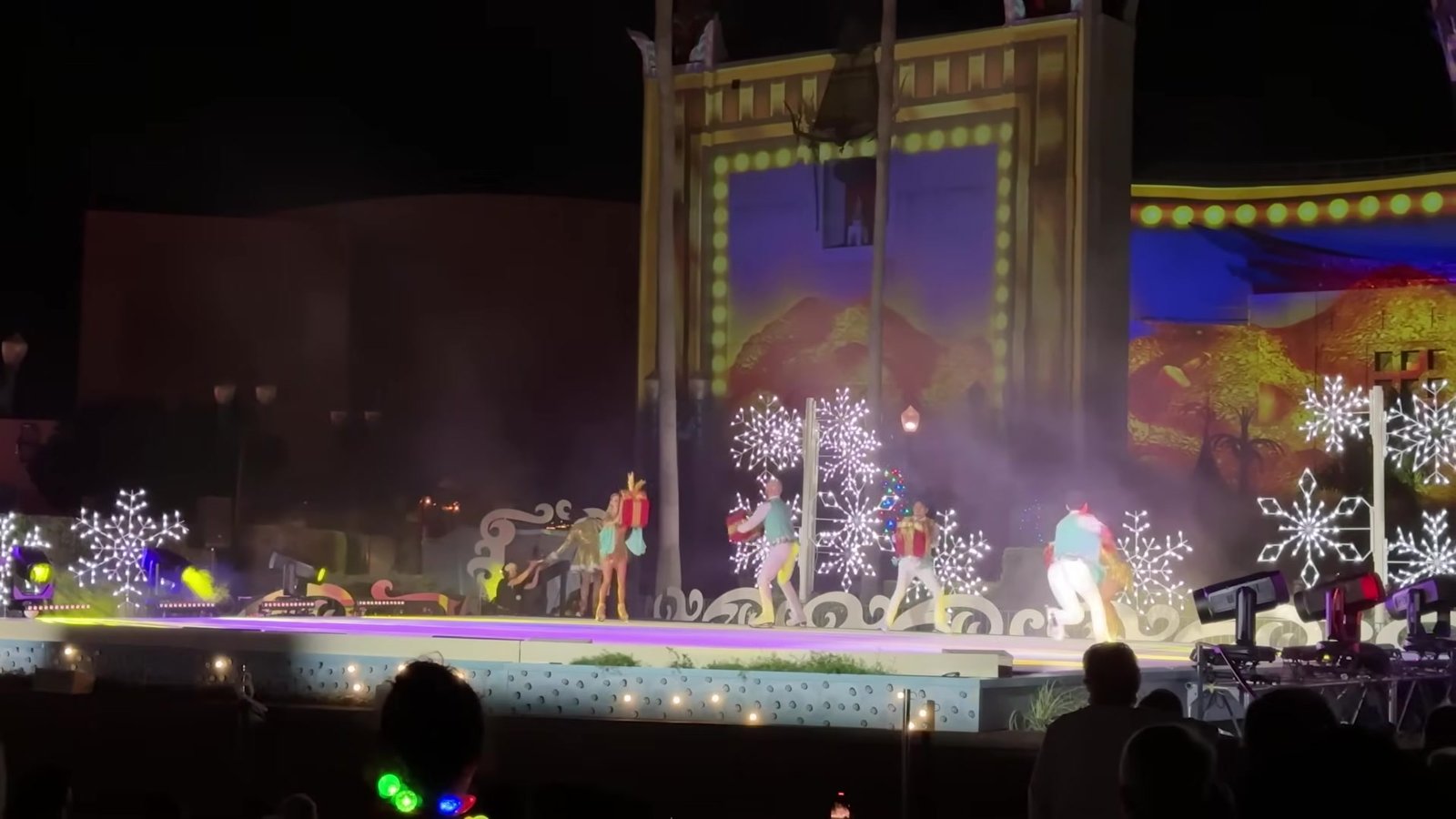 Palco do Teatro Chinês com cenário de Natal, flocos de neve e artistas se apresentando no Jollywood Nights