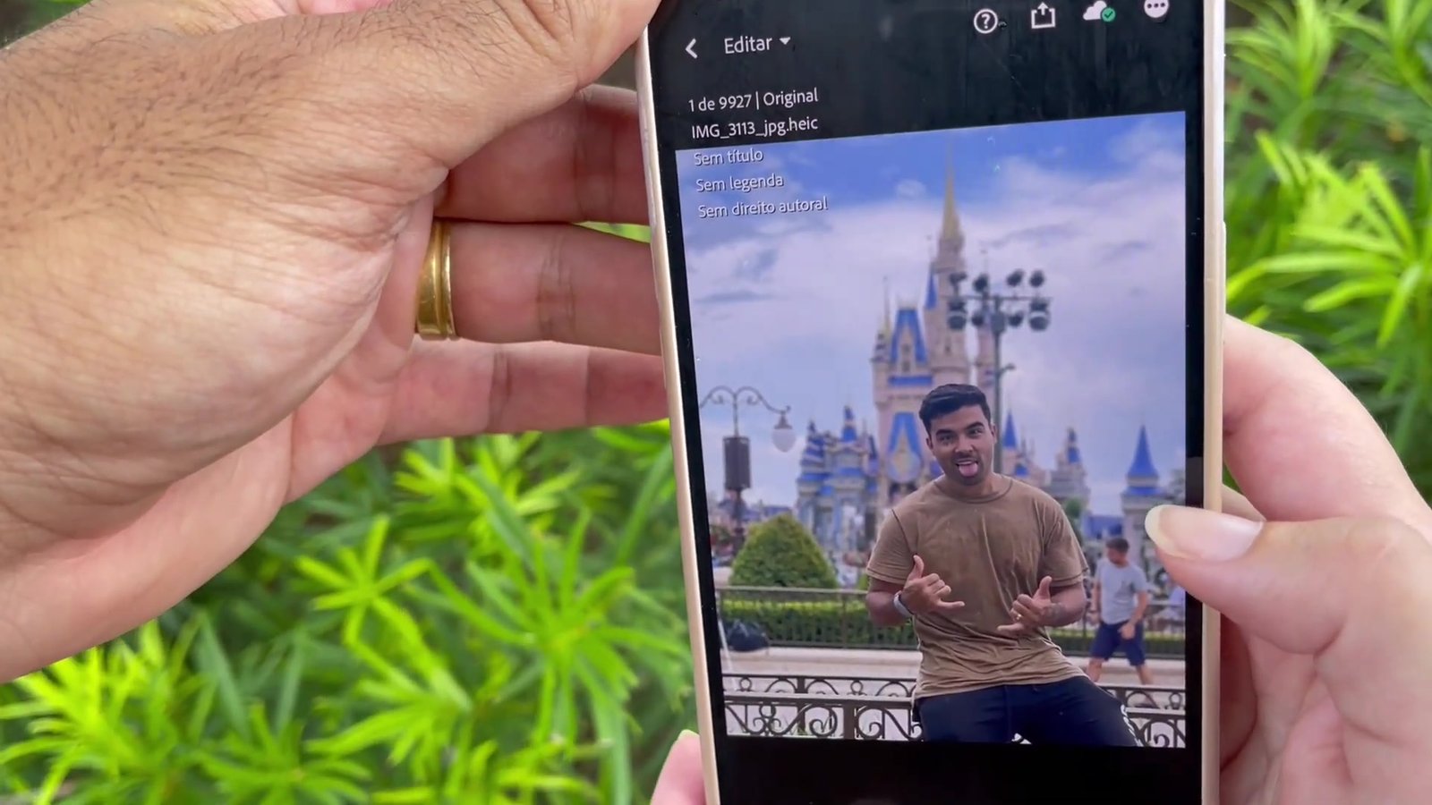 Celular mostrando a foto do Gustavo apoiado na gradinha com o Castelo da Cinderela ao fundo