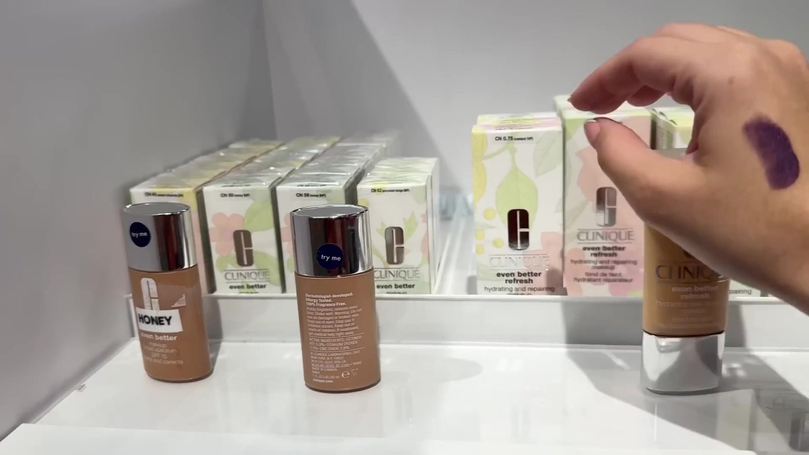 Bases Even Better da Clinique na prateleira, com uma mancha roxa do teste no braço