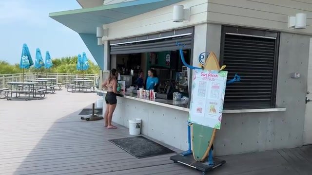 Quiosque do Siesta Sun Deck na Siesta Beach, com guarda-sóis azuis e o cardápio na entrada
