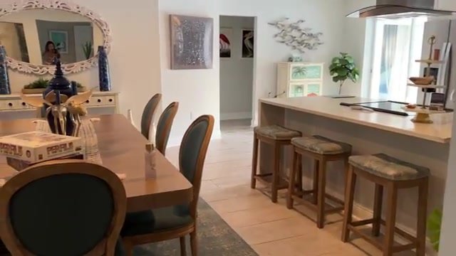 Cozinha e sala de jantar integradas da casa de temporada em Sarasota, com bancada, banquetas e decoração praiana