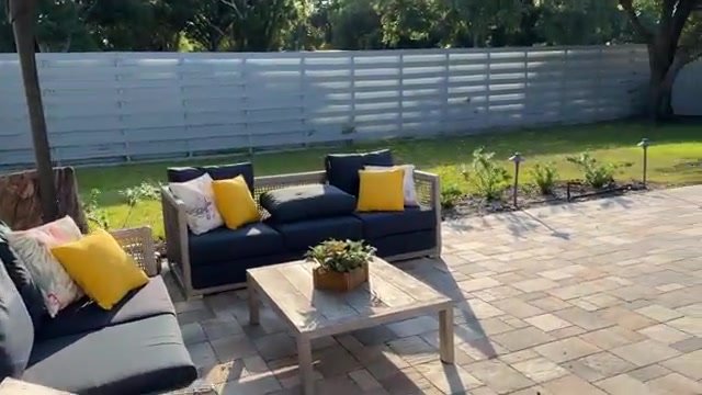 Área externa da casa de temporada em Sarasota com sofás, almofadas amarelas e jardim gramado