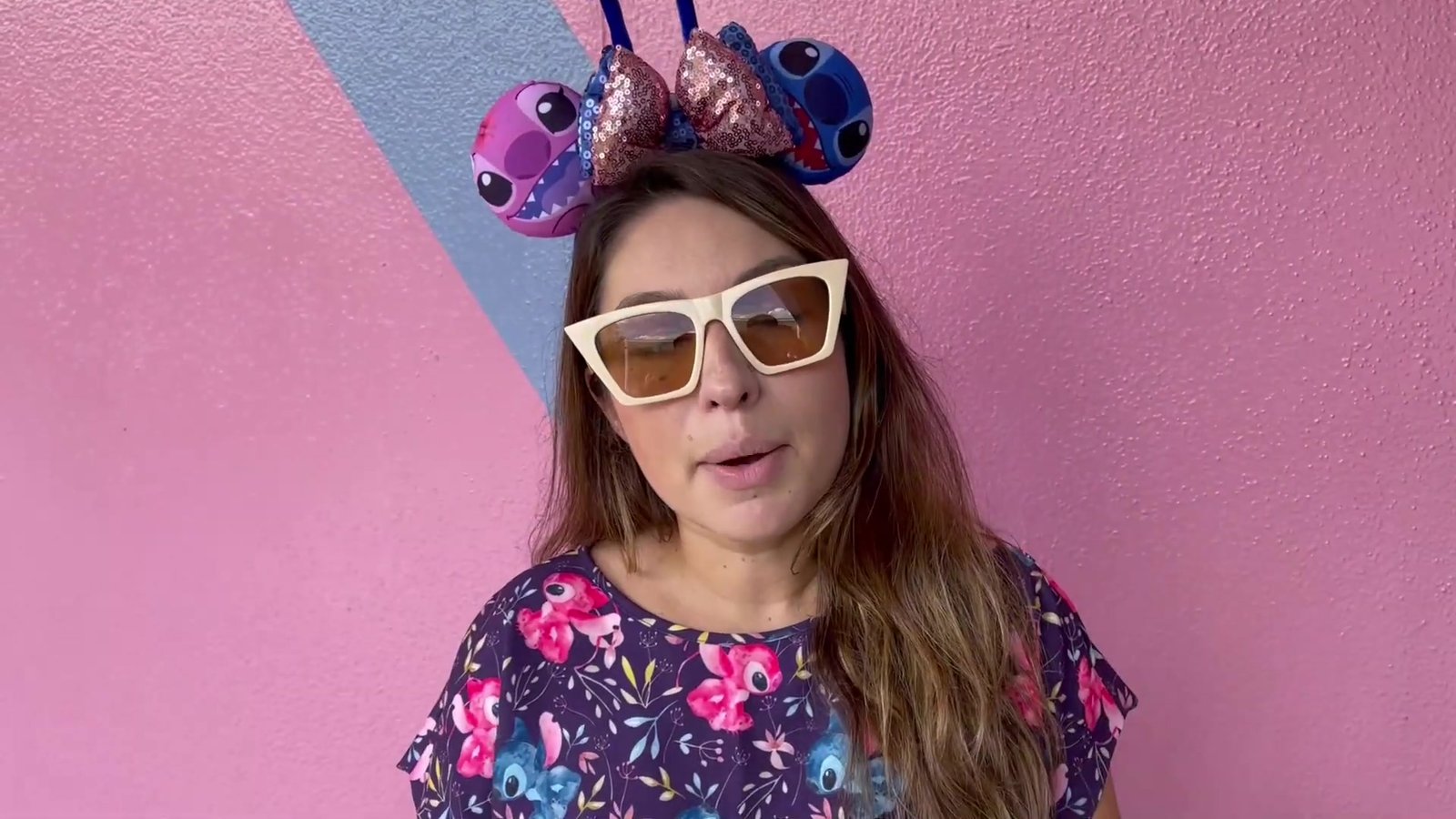 Gabi do Turistorlando de orelhas do Stitch na parede rosa do Epcot, ponto clássico de foto do PhotoPass