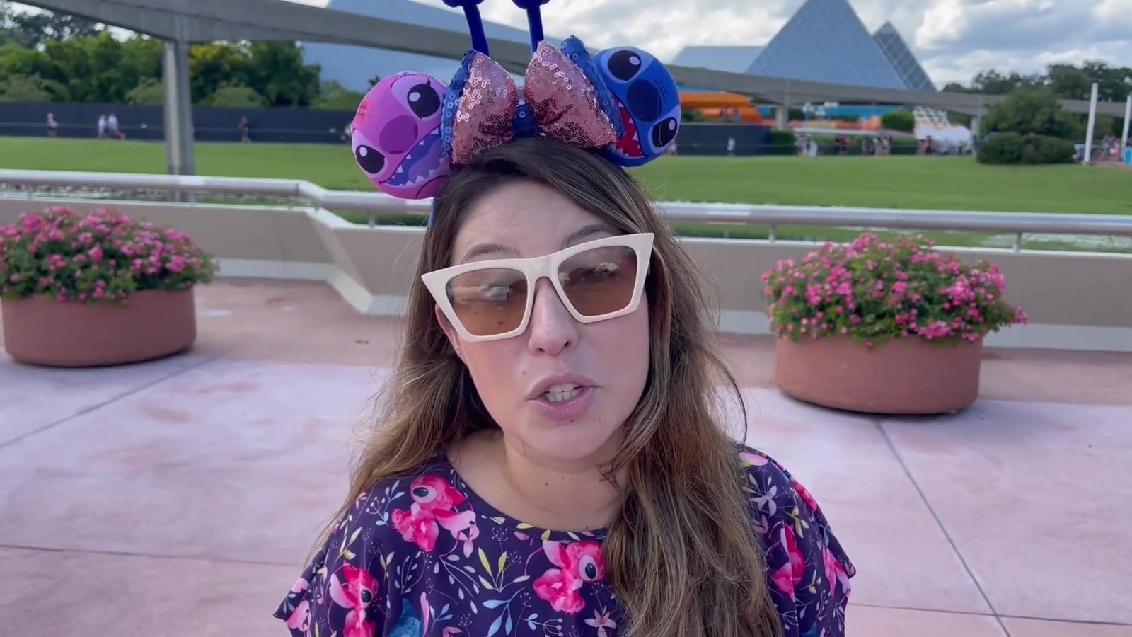 Gabi do Turistorlando explicando o Memory Maker em frente aos jardins e à Spaceship Earth do Epcot