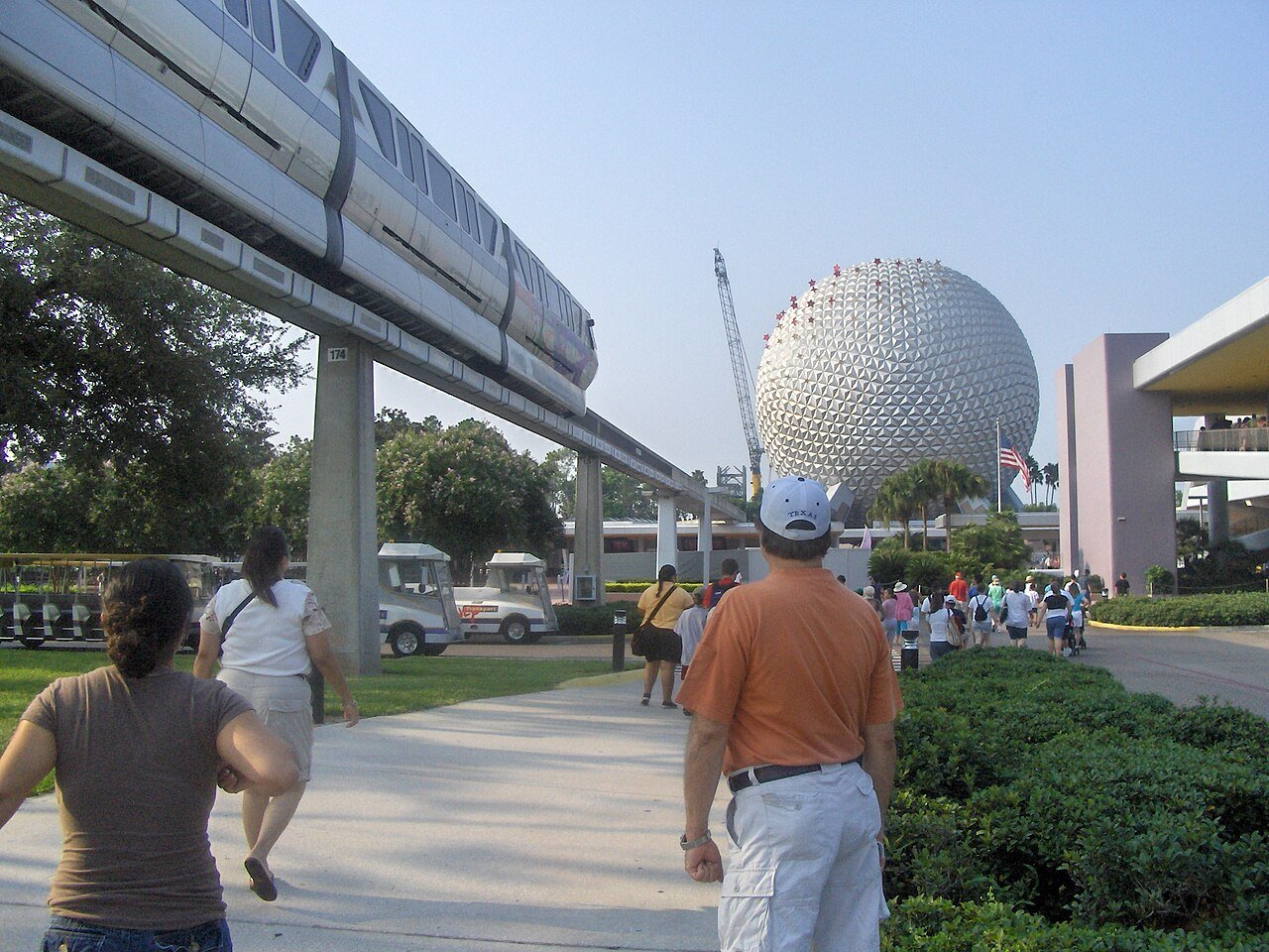 Visitantes caminhando na entrada do Epcot com a Spaceship Earth e o monotrilho ao fundo